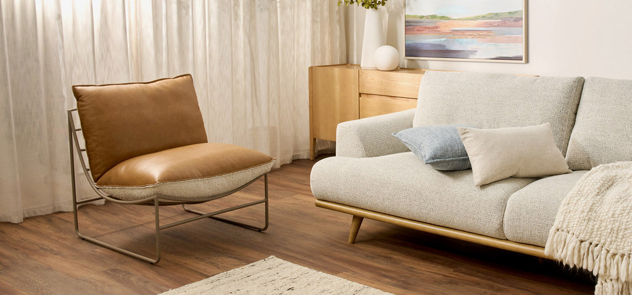 Sculptural single armchair in a natural fabric, positioned in a modern living room with a dark grey low sideboard behind, creating a minimalist and elegant contrast.