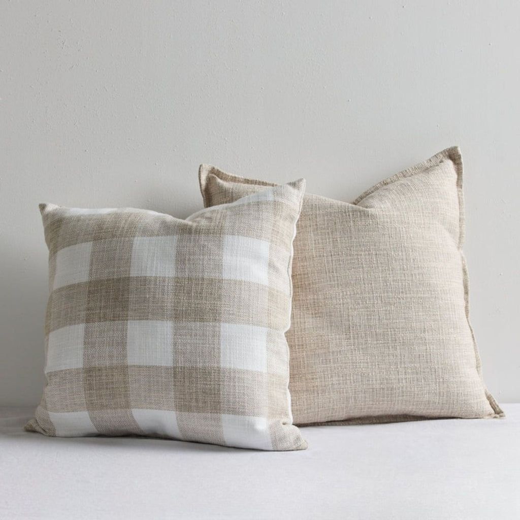 two-natural-linen-cushions-leaning-against-a-white-wall
