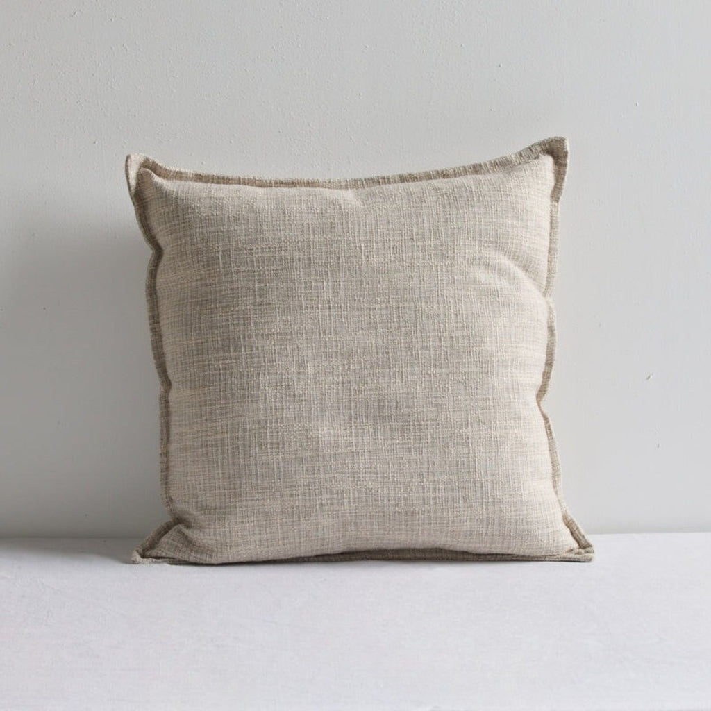 Beige natural linen cushion leaning against a white wall