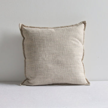 Beige natural linen cushion leaning against a white wall