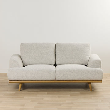 Beige 2 seat sofa with a warm timber base  on paket floor. 